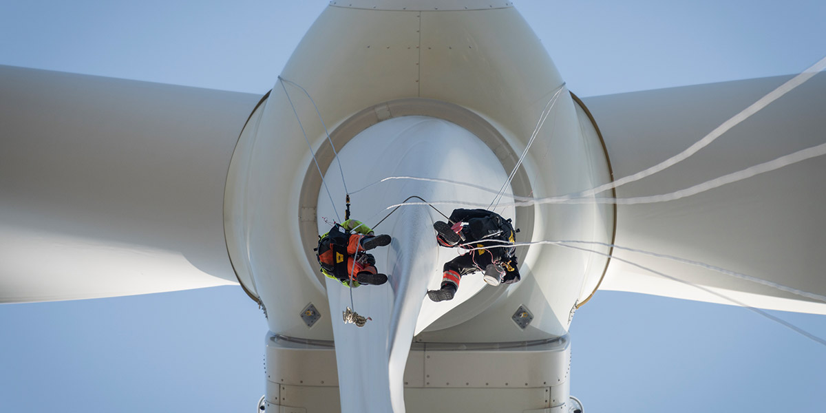 wind turbine workers hanging off blade