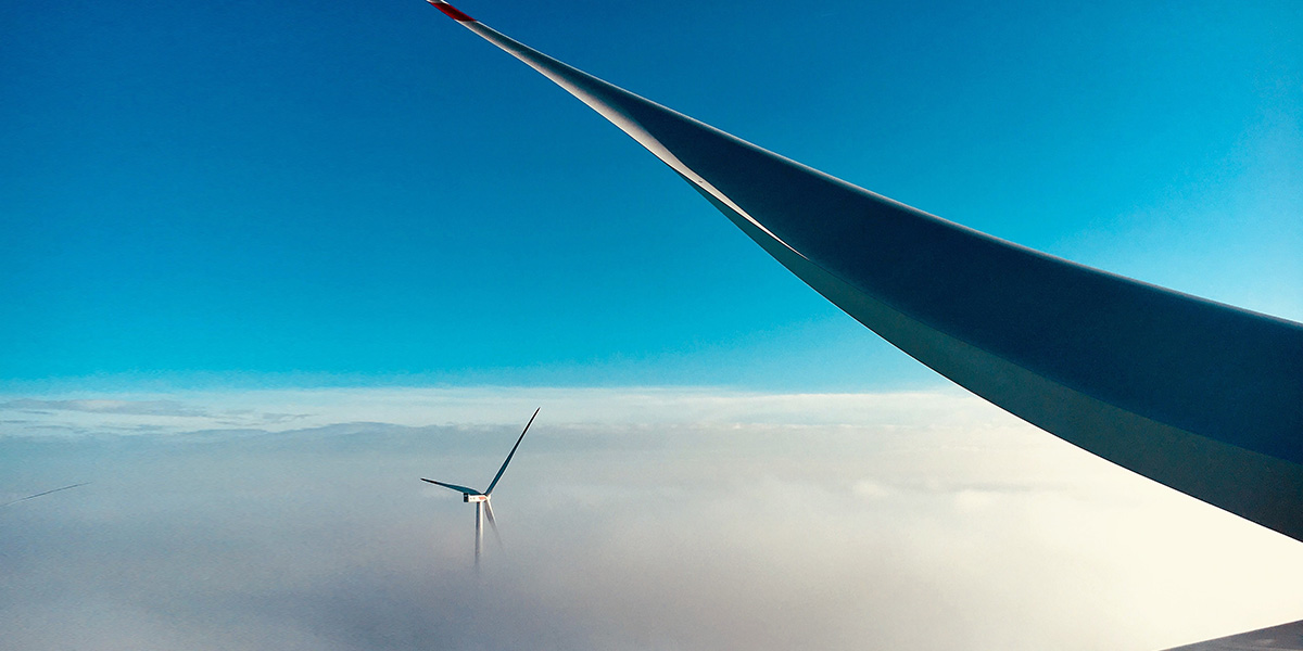 Wind turbine above clouds, blue and clear sky